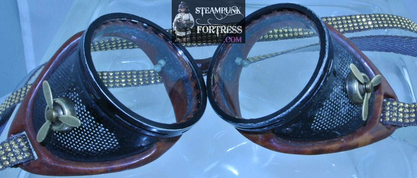 BROWN BAKELITE GOGGLES VINTAGE BLACK MESH SIDE GOLD KINETIC SPINNING SPINS PROPELLERS ON EACH SIDE 3 ROW GOLD STUDS RIBBON GOGGLES STARR WILDE STEAMPUNK FORTRESS